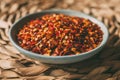 Heap of chili flakes in a bowl. Red cayenne pepper crushed. Close up view of red chili flakes as background for design.