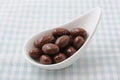 A heap of chocolate covered almonds on a plate on tablecloth Royalty Free Stock Photo