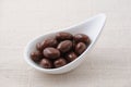 A heap of chocolate covered almonds on a plate on tablecloth Royalty Free Stock Photo