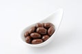 A heap of chocolate covered almonds on a plate on white background Royalty Free Stock Photo