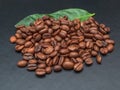 Heap of coffee beans with coffee leaves on a black background. Close-up Royalty Free Stock Photo