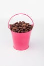 Heap coffee beans in pink bucket on white background