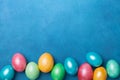 Heap of colorful eggs on blue table top view. Holiday Easter banner. Copy space for text.