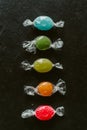 Heap of colorful fruity candies on black slate background. Close up view of different multicolored candies.