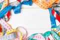 Heap of colorful measuring tapes in the form of frame on wooden background. Top view of slim waist concept with copy space