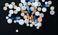 Heap of colorful pills, pharmaceutical medicine tablets and capsules over black background Royalty Free Stock Photo