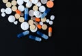 Heap of colorful pills, pharmaceutical medicine tablets and capsules over black background Royalty Free Stock Photo