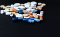 Heap of colorful pills, pharmaceutical medicine tablets and capsules over black background Royalty Free Stock Photo