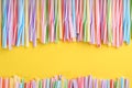 Heap of colorful plastic drinking straws on yellow background, flat lay. Space for text Royalty Free Stock Photo