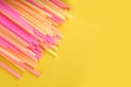 Heap of colorful plastic drinking straws on yellow background, flat lay. Space for text Royalty Free Stock Photo