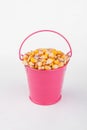 Heap corn grains in pink bucket on white background Royalty Free Stock Photo