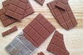 Cracked chocolate bars scattered on wooden table Royalty Free Stock Photo