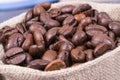 Heap of dark roasted fragrant coffee beans in jute bag