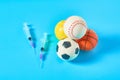 Heap of different balls near syringe on blue background. Concept of doping in professional sport