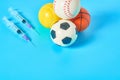 Heap of different balls near syringe on blue background. Concept of doping in professional sport