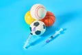 Heap of different balls near syringe on blue background. Concept of doping in professional sport