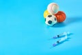 Heap of different balls near syringe on blue background. Concept of doping in professional sport