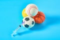 Heap of different balls near syringe on blue background. Concept of doping in professional sport