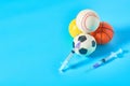 Heap of different balls near syringe on blue background. Concept of doping in professional sport