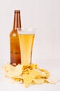 Heap different crispy golden snacks and beer in glass, brown bottle on soft white wood background. Royalty Free Stock Photo