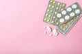 Heap of different pills, in blisters and scattered on pink background. Pharmacy and healthcare theme. Copy space