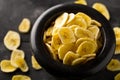 Heap of dried banana chips snack in black bowl on rustic table Royalty Free Stock Photo