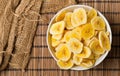 Heap of dried banana chips snack in white bowl on bamboo mat Royalty Free Stock Photo