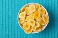 Heap of dried banana chips snack in white bowl on blue turquoise Royalty Free Stock Photo