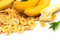 Heap of dried banana chips with yellow banana bunch and green leaves