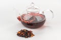 Heap of dried berries and fruit pieces and a glass teapot with brewing tisane