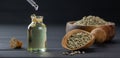 Heap of dried organic hemp seeds or cannabis plant seeds in spoon and bowl with glass of hemp seed oil on wooden backdrop