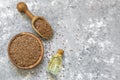 Heap of Flax seeds or linseeds in spoon or bowl with glass of flax seed oil on rustic backdrop Royalty Free Stock Photo