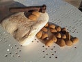 Heap of fresh almonds, flat stone, and a rusty hammer for smashing the nuts on the table