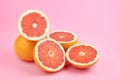 Heap of fresh cut grapefruit fruits on trendy pink paper background