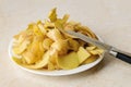Heap of fresh potato peels and small vegetable knife on a white plate ober kitchen table. Cook boiled potatoes at home. Household Royalty Free Stock Photo