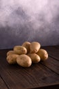 Heap of fresh potatoes on rustic wooden surface and slate textured background. Organic food, carbs, tubers. Royalty Free Stock Photo