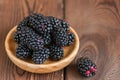 Heap of fresh raw blackberries in a plate on a wooden background Royalty Free Stock Photo