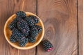 Heap of fresh raw blackberries in a plate on a wooden background Royalty Free Stock Photo