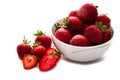 Heap of fresh strawberry put in white ceramic bowl, and some strawberry spread on white table.