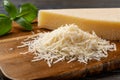 Heap of grated grana padano cheese closeup. Tasty parmesan grated and whole wedge over wooden cutting board. Delicious dairy