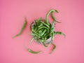 A heap of green chillies scattered on a pink surface bag