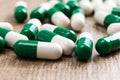 Heap of green and white capsules on wooden background. Royalty Free Stock Photo