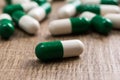 Heap of green and white capsules on wooden background. One pill Royalty Free Stock Photo