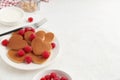 A heap of heart shaped pancakes with raspberries and a fork on the white plate on white background