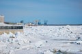 A heap of ice floes on the Amur River during the spring ice drift. Cranes of the river port and the buildings of the