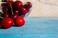 A heap and a large glass bowl of fresh red ripe cherries and green leaves of a cherry tree Royalty Free Stock Photo