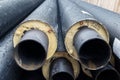 Heap of many new black insulated steel pipes at municipal construction site outdoors. Heating main district pipeline