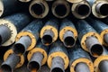 Heap of many new black insulated steel pipes at municipal construction site outdoors. Heating main district pipeline