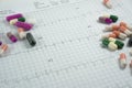 Heap of medicine pills on cardiogram grid paper. Royalty Free Stock Photo