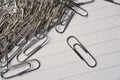 Heap of metal paper clips on white lined paper notepad as a symbol of typical office environment Royalty Free Stock Photo